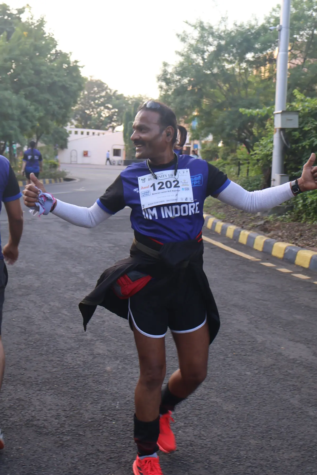A runner spreading both arms wide mid-race