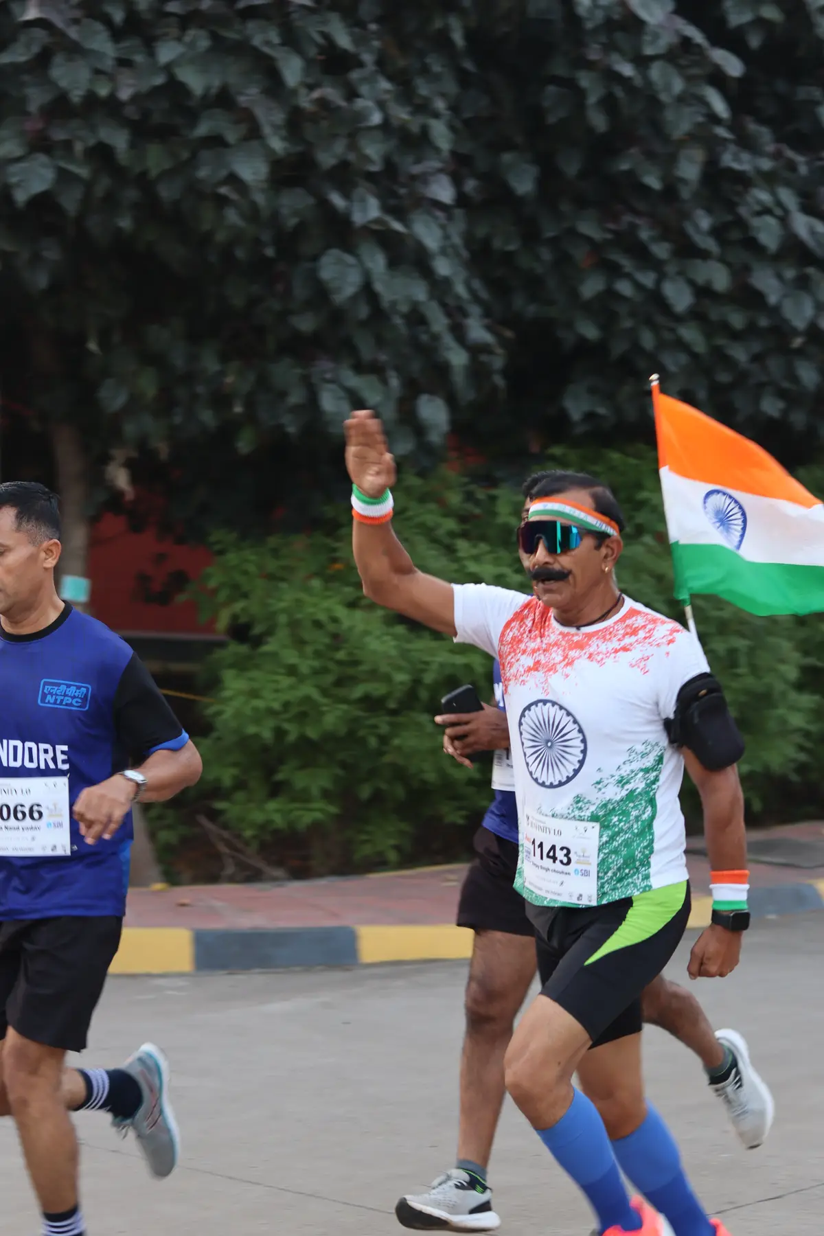 A runner in tricolour waving the flag mid-race